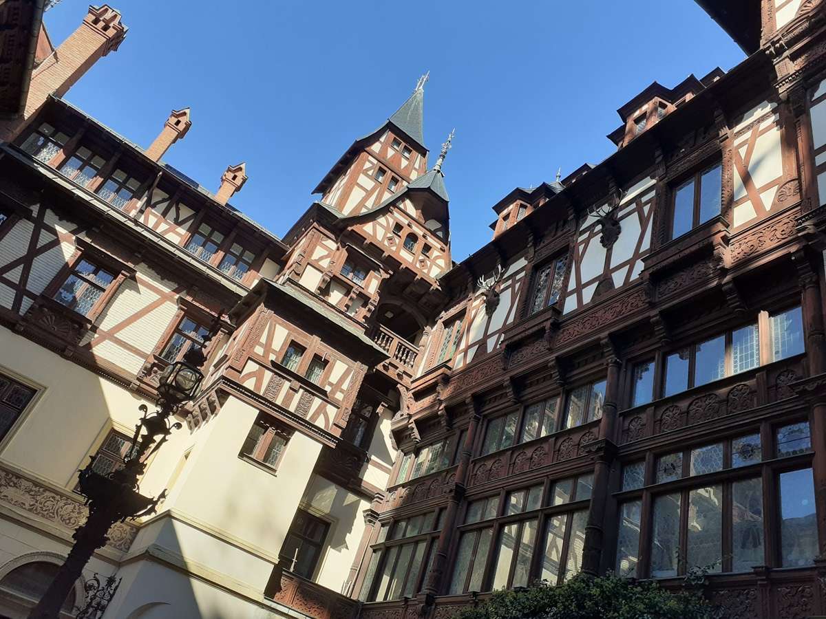 Cortile interno del castello di Peles in Transilvania, con le mura affrescate tetti e cornici di legno